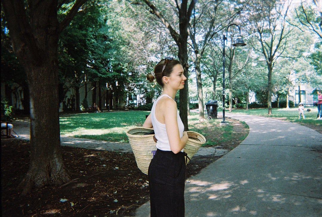 White ribbed tank top, black linen pants, straw tote